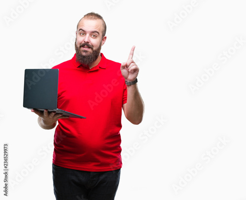 Young caucasian man using computer laptop over isolated background surprised with an idea or question pointing finger with happy face, number one