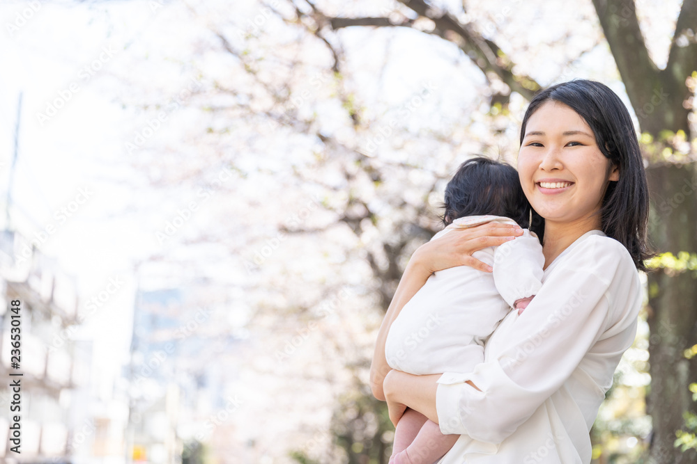 portrait of young asian mother and baby looking cherry blossom