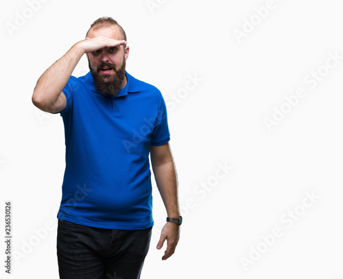 Young caucasian hipster man wearing blue shirt over isolated background very happy and smiling looking far away with hand over head. Searching concept.