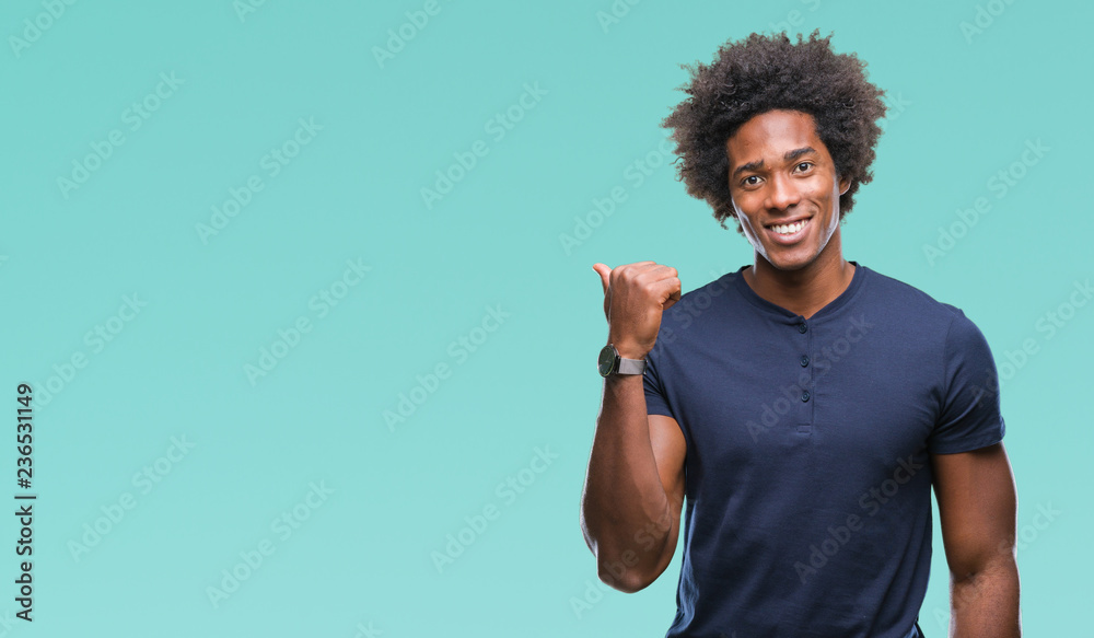 Afro american man over isolated background smiling with happy face looking and pointing to the side with thumb up. Afro american man over isolated background smiling with happy face looking and pointing to the side with thumb up.