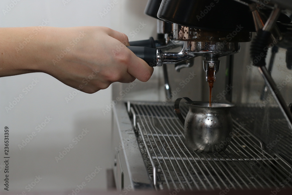 Espresso machine brewing a coffee and barista hold coffee cone