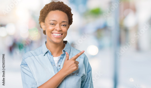 Young beautiful african american woman over isolated background cheerful with a smile of face pointing with hand and finger up to the side with happy and natural expression on face