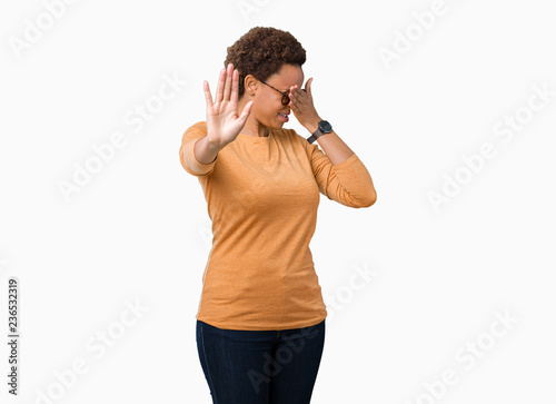 Young beautiful african american woman wearing glasses over isolated background covering eyes with hands and doing stop gesture with sad and fear expression. Embarrassed and negative concept.