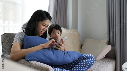 mother and son playing mobile phone in living room