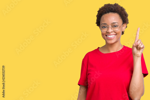Beautiful young african american woman wearing glasses over isolated background showing and pointing up with finger number one while smiling confident and happy. © Krakenimages.com
