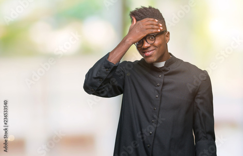 Young african american priest man over isolated background surprised with hand on head for mistake, remember error. Forgot, bad memory concept.