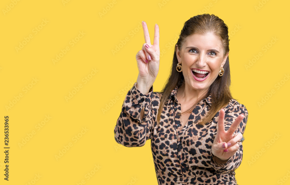 Beautiful middle age mature rich woman wearing leopard dress over isolated background smiling looking to the camera showing fingers doing victory sign. Number two.
