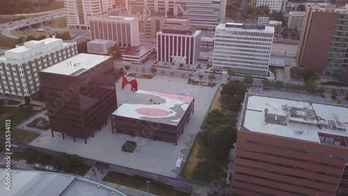 Aerial view of City Hall and La Grande Vitesse sculpture on Calder Plaza in Grand Rapids, Michigan, USA. Sunset in background. Drone moves upward and circles to the right among other nearby buildings. photo