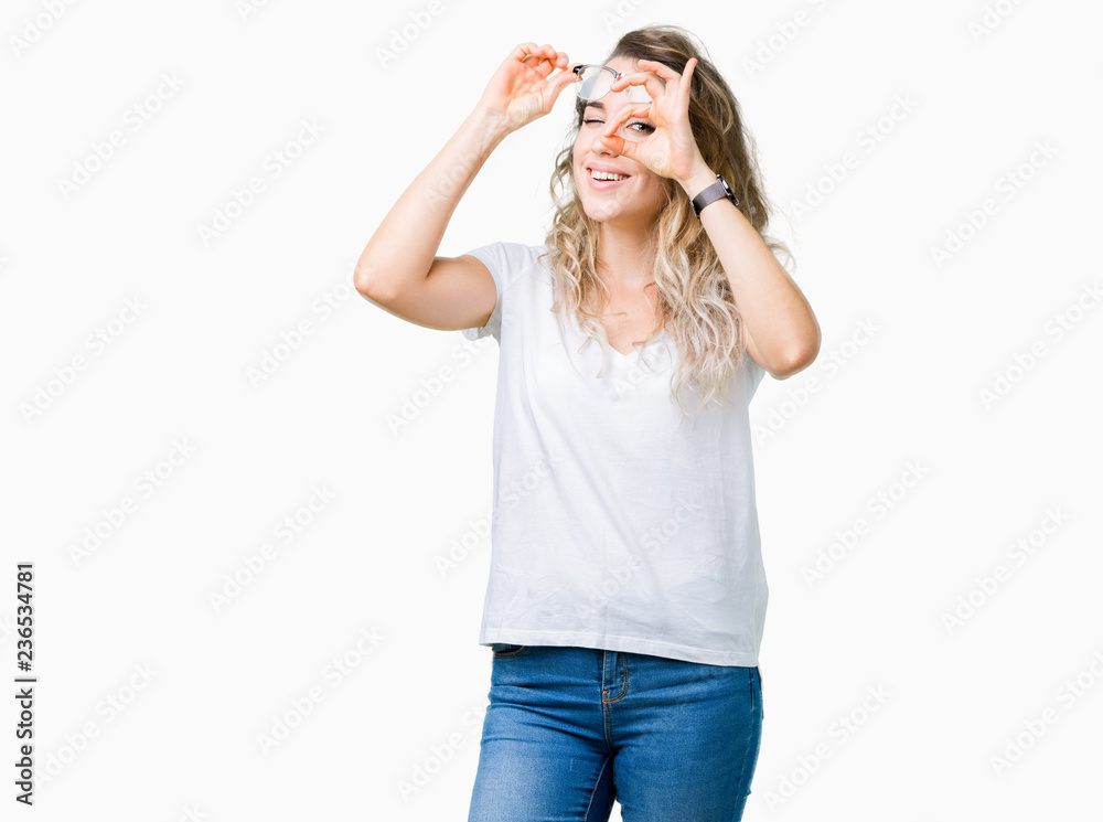 Beautiful young blonde woman wearing glasses over isolated background doing ok gesture with hand smiling, eye looking through fingers with happy face. Beautiful young blonde woman wearing glasses over isolated background doing ok gesture with hand smiling, eye looking through fingers with happy face.