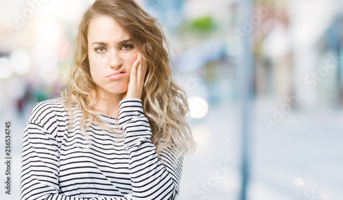 Fototapeta Naklejka Na Ścianę i Meble -  Beautiful young blonde woman wearing stripes sweater over isolated background thinking looking tired and bored with depression problems with crossed arms.