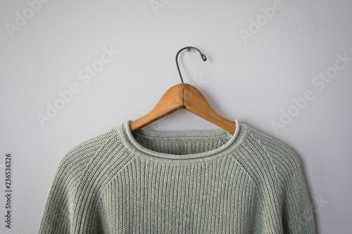 Light green sweater hanging on grey wall photo