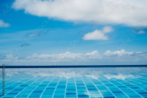 Infinite swimming pool with reflection of ocean and clouds in the water