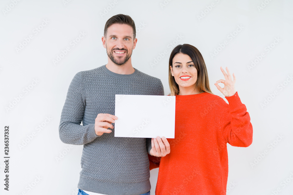 Young couple holding blank sheet paper over isolated background doing ok sign with fingers, excellent symbol Young couple holding blank sheet paper over isolated background doing ok sign with fingers, excellent symbol