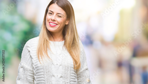 Young beautiful woman casual white sweater over isolated background winking looking at the camera with sexy expression, cheerful and happy face. © Krakenimages.com