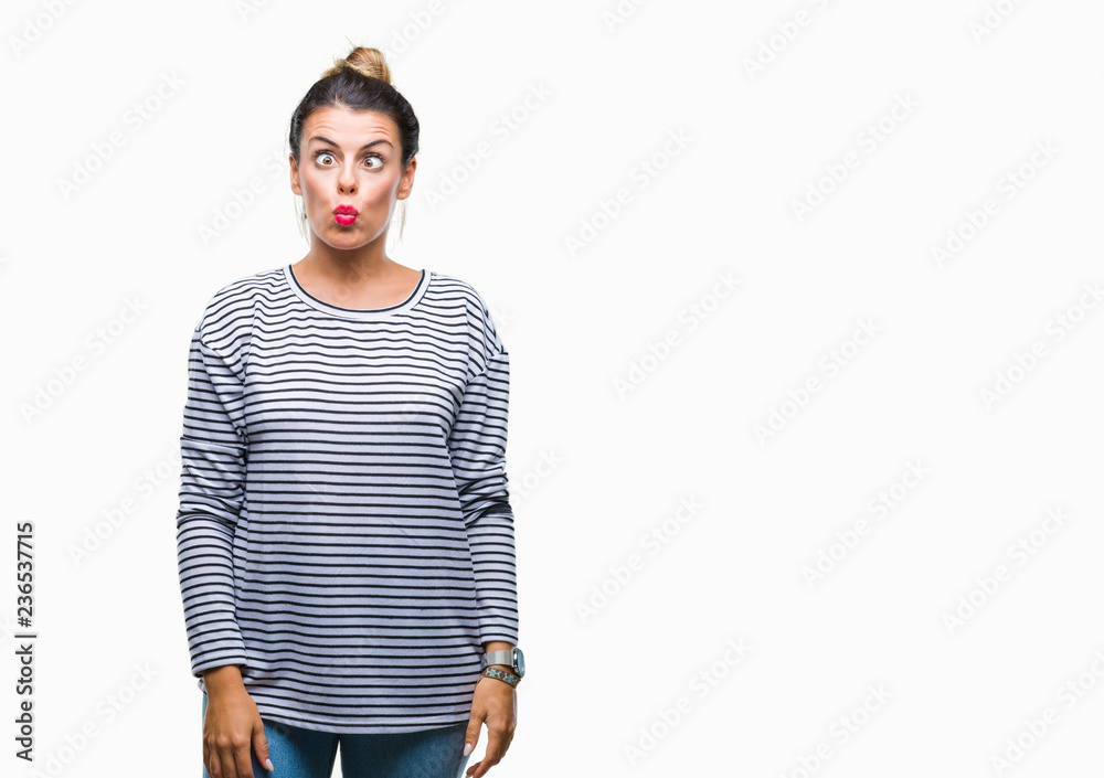 Fototapeta premium Young beautiful woman casual stripes sweater over isolated background making fish face with lips, crazy and comical gesture. Funny expression.