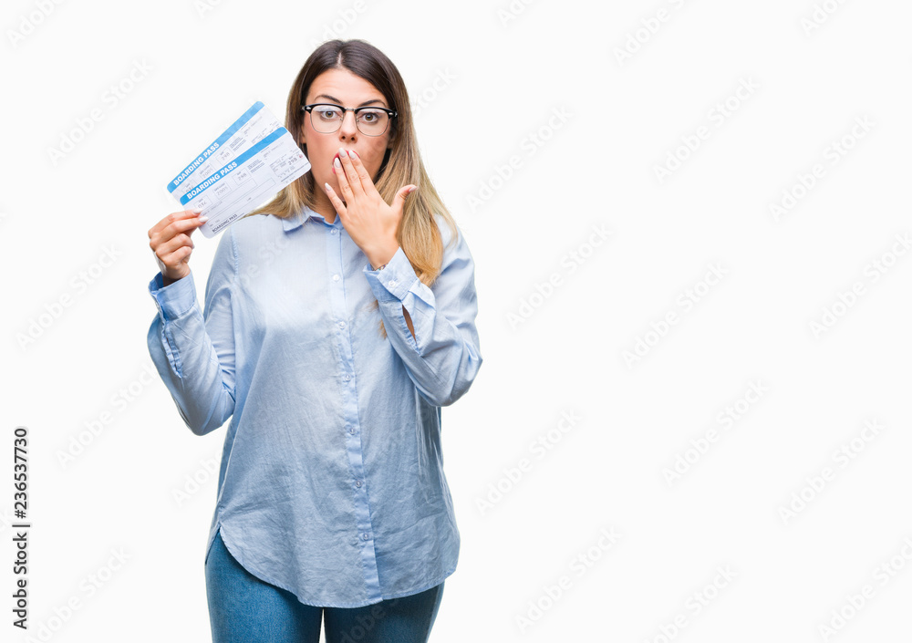 Young beautiful woman holding boarding pass over isolated background cover mouth with hand shocked with shame for mistake, expression of fear, scared in silence, secret concept Young beautiful woman holding boarding pass over isolated background cover mouth with hand shocked with shame for mistake, expression of fear, scared in silence, secret concept