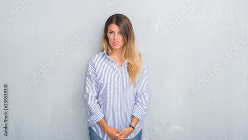 Young adult woman over grey grunge wall wearing fashion business outfit skeptic and nervous, frowning upset because of problem. Negative person. © Krakenimages.com
