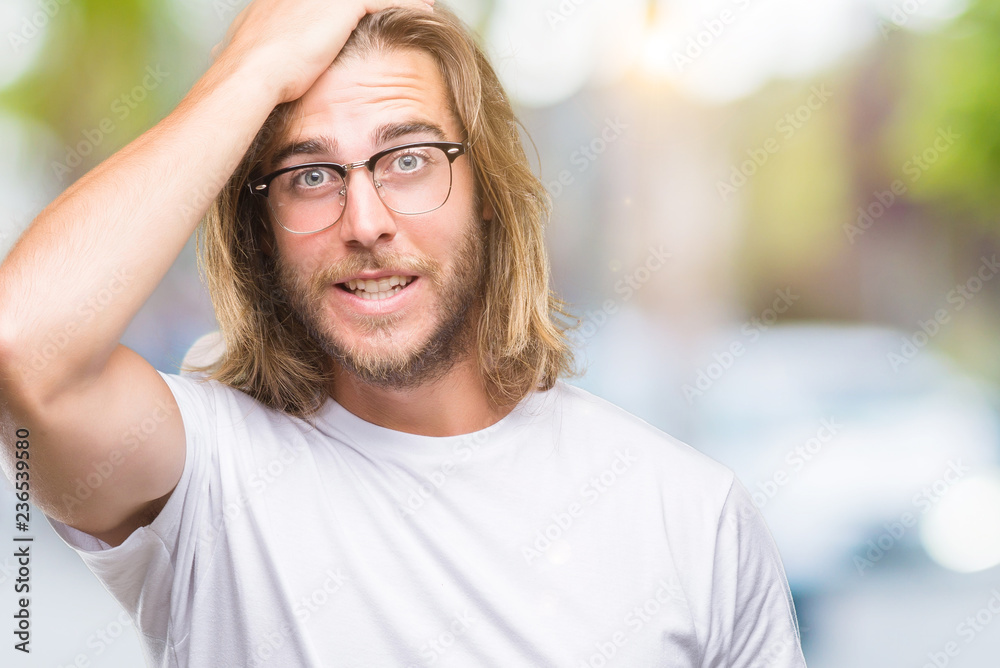 Young handsome man with long hair wearing glasses over isolated background surprised with hand on head for mistake, remember error. Forgot, bad memory concept. Young handsome man with long hair wearing glasses over isolated background surprised with hand on head for mistake, remember error. Forgot, bad memory concept.