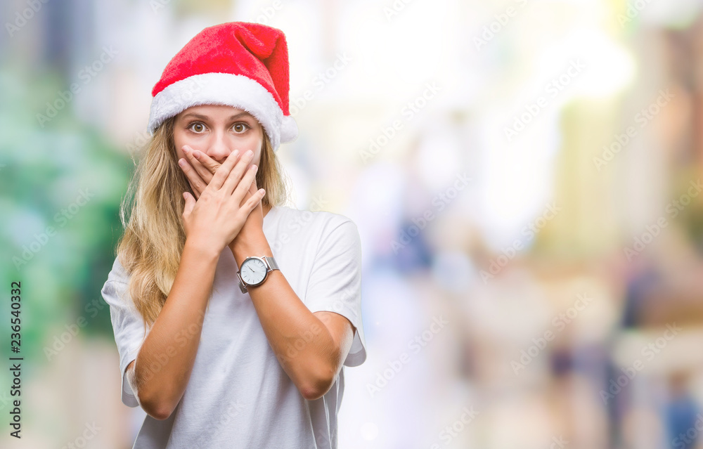 Young beautiful blonde woman wearing christmas hat over isolated background shocked covering mouth with hands for mistake. Secret concept.