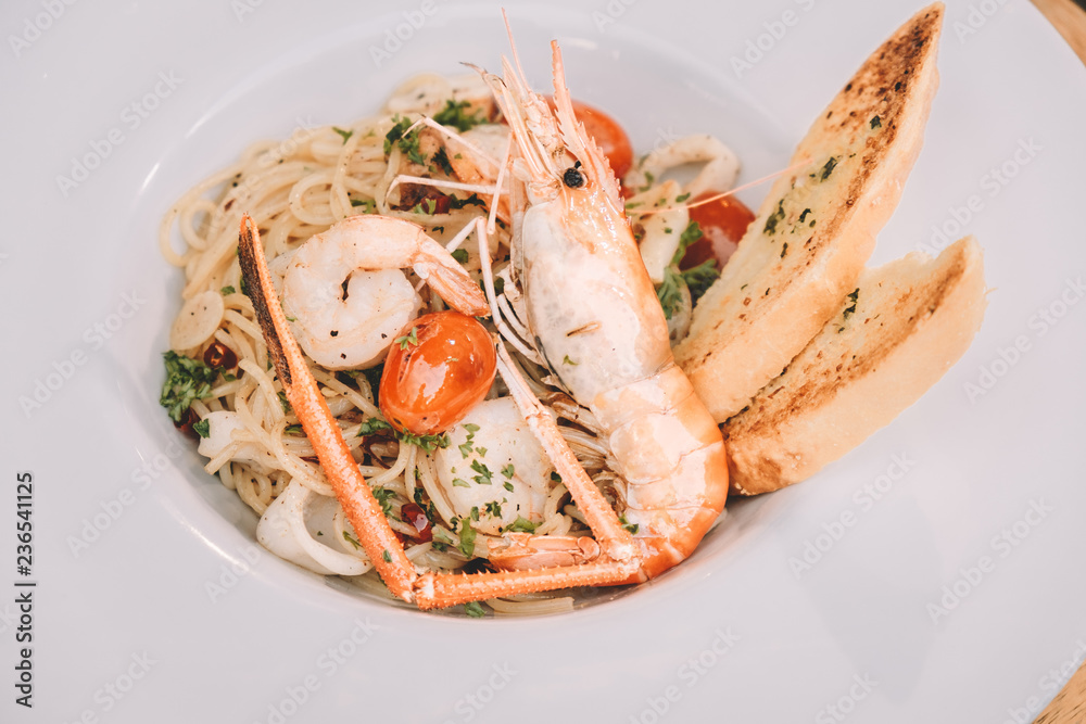 spaghetti pasta with shrimps and sweet basil on white plate over wooden table spaghetti pasta with shrimps and sweet basil on white plate over wooden table