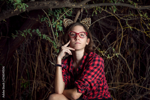 Teen Girl with Leopard Ears Sits Contemplatively in Front of a Thicket of Tangeled Branches photo