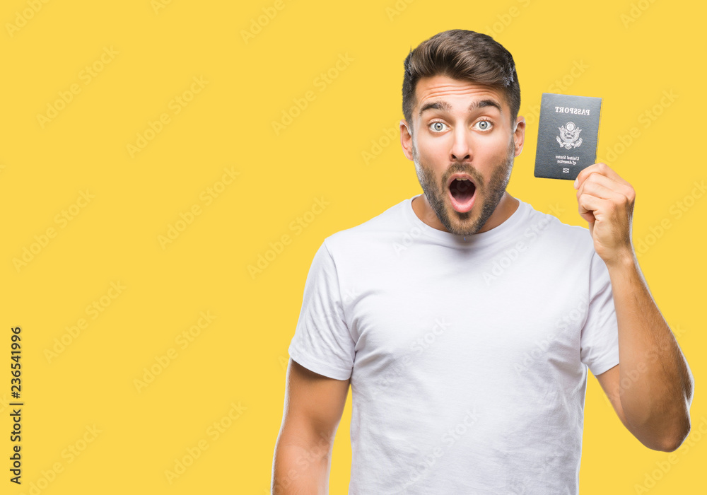 Young handsome man holding passport of united states over isolated background scared in shock with a surprise face, afraid and excited with fear expression Young handsome man holding passport of united states over isolated background scared in shock with a surprise face, afraid and excited with fear expression
