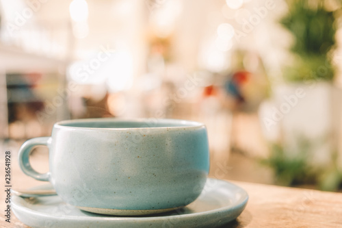 Ceramic Pastel Blue Tea cup on the wooden table with blur cafe background soft focus