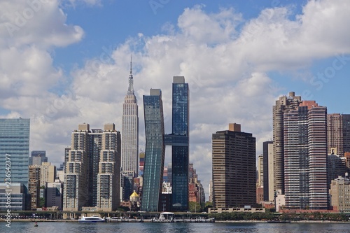 New York, New York, USA: View of the midtown Manhattan skyline from Long Island City, on the east side of the East river, under a blue sky with white clouds.