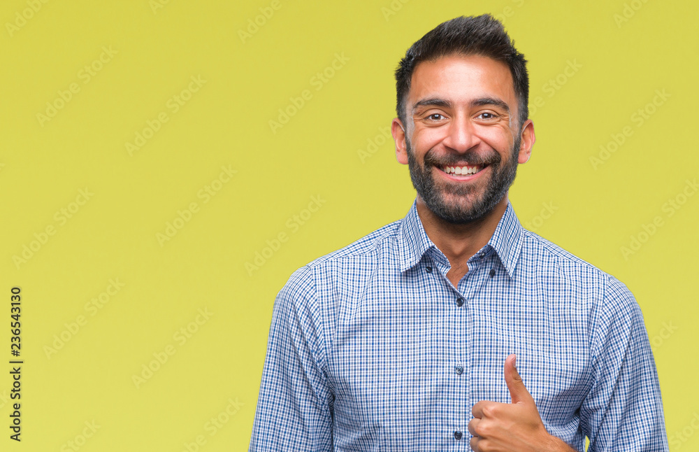 Adult hispanic man over isolated background doing happy thumbs up gesture with hand. Approving expression looking at the camera with showing success.