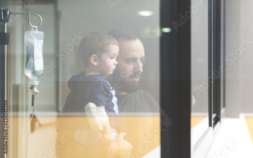 Father holding his son in arms looking through the window photo