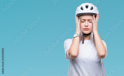 Young blonde woman wearing cyclist security helmet over isolated background suffering from headache desperate and stressed because pain and migraine. Hands on head.