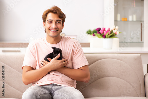 Young man playing with kitten at home