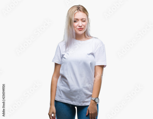 Young blonde woman over isolated background winking looking at the camera with sexy expression, cheerful and happy face.