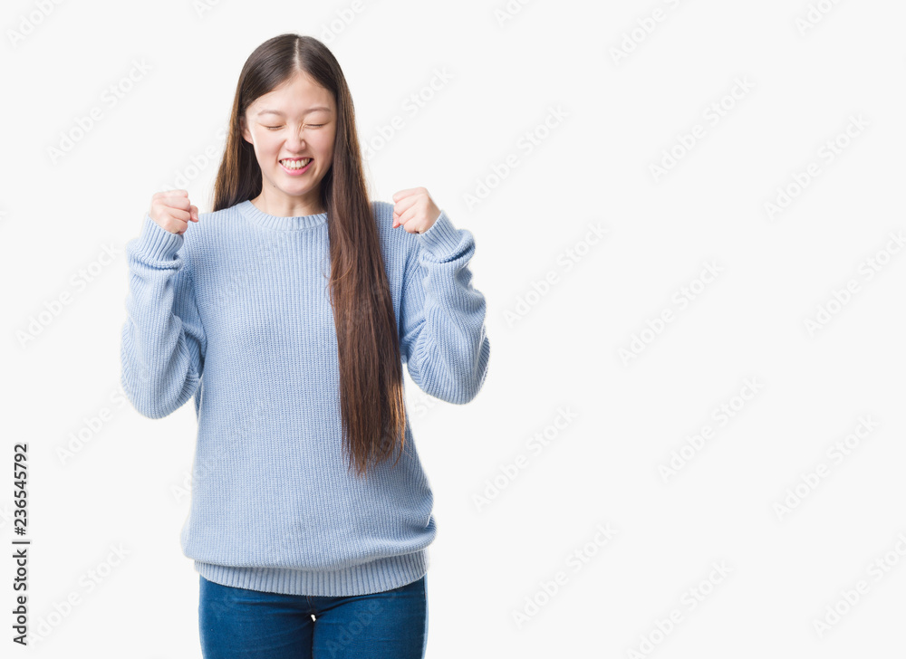 Young Chinese woman over isolated background excited for success with arms raised celebrating victory smiling. Winner concept. Young Chinese woman over isolated background excited for success with arms raised celebrating victory smiling. Winner concept.