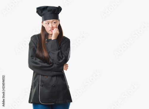 Young Chinese woman over isolated background wearing chef uniform looking stressed and nervous with hands on mouth biting nails. Anxiety problem.