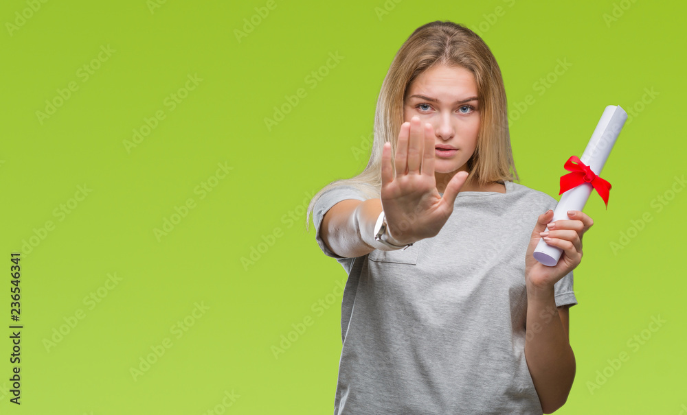 Young caucasian woman holding degree over isolated background with open hand doing stop sign with serious and confident expression, defense gesture Young caucasian woman holding degree over isolated background with open hand doing stop sign with serious and confident expression, defense gesture