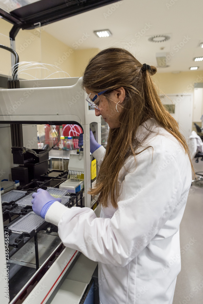 Female scientist working with a genome sequencing machine in a DNA laboratory Female scientist working with a genome sequencing machine in a DNA laboratory
