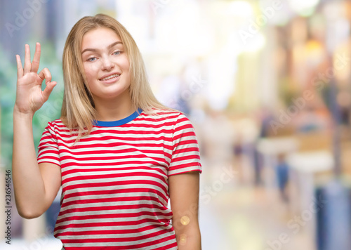 Young caucasian woman over isolated background smiling positive doing ok sign with hand and fingers. Successful expression.