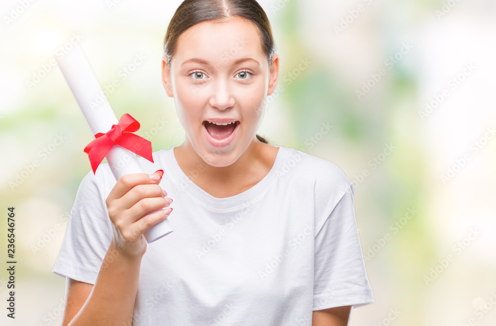 Young caucasian woman holding degree over isolated background scared in shock with a surprise face, afraid and excited with fear expression Young caucasian woman holding degree over isolated background scared in shock with a surprise face, afraid and excited with fear expression