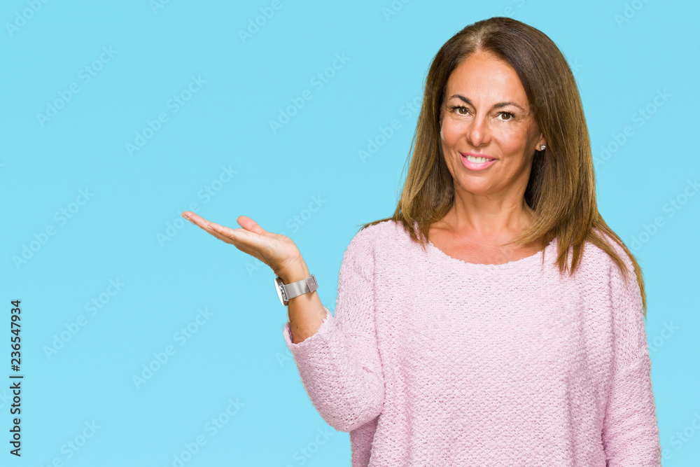 Beautiful middle age adult woman wearing winter sweater over isolated background smiling cheerful presenting and pointing with palm of hand looking at the camera. Beautiful middle age adult woman wearing winter sweater over isolated background smiling cheerful presenting and pointing with palm of hand looking at the camera.