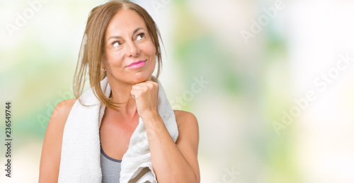 Beautiful middle age woman wearing sport clothes and a towel over isolated background with hand on chin thinking about question, pensive expression. Smiling with thoughtful face. Doubt concept.