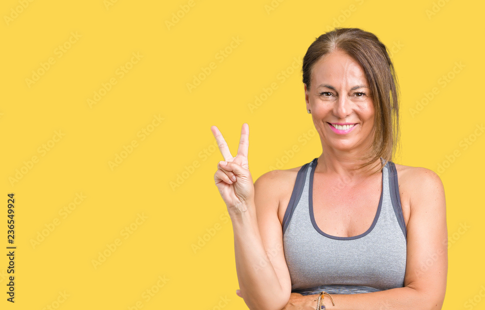 Beautiful middle age woman wearing sport clothes over isolated background smiling with happy face winking at the camera doing victory sign. Number two. Beautiful middle age woman wearing sport clothes over isolated background smiling with happy face winking at the camera doing victory sign. Number two.