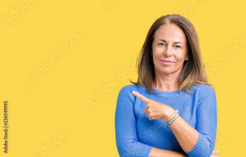 Middle age beautiful woman wearing winter sweater over isolated background Pointing with hand finger to the side showing advertisement, serious and calm face