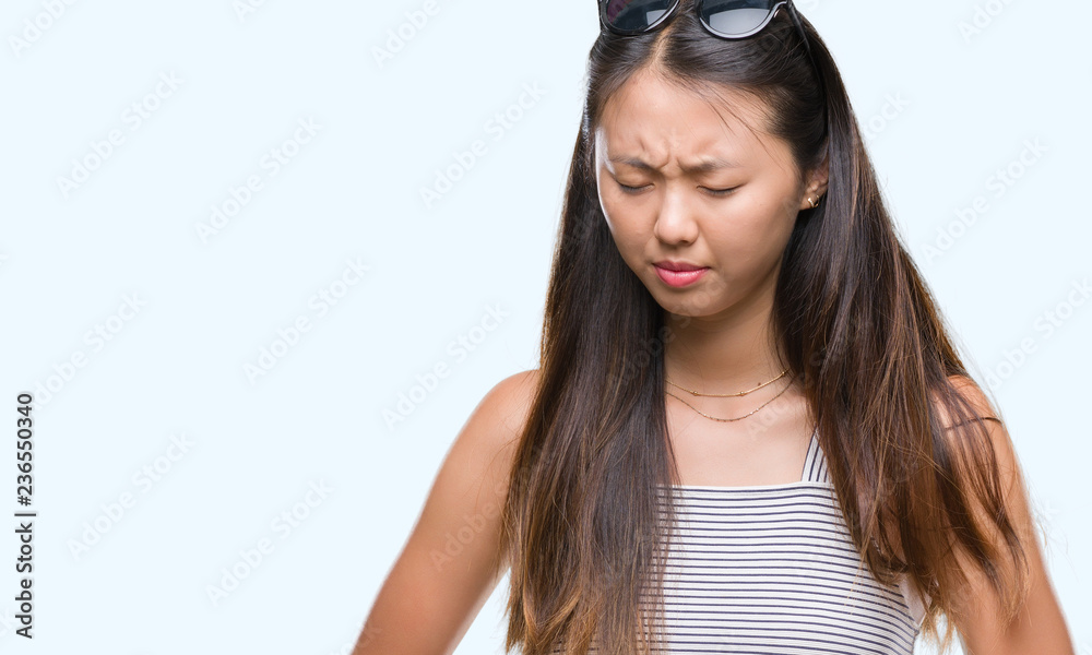 Obraz premium Young asian woman wearing sunglasses over isolated background with hand on stomach because indigestion, painful illness feeling unwell. Ache concept.