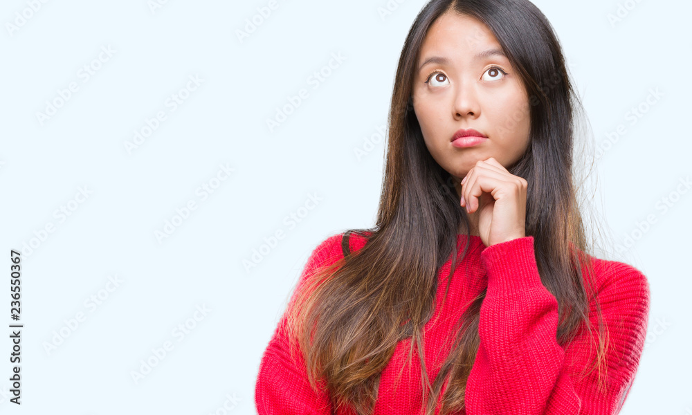 Young asian woman wearing winter sweater over isolated background with hand on chin thinking about question, pensive expression. Smiling with thoughtful face. Doubt concept. Young asian woman wearing winter sweater over isolated background with hand on chin thinking about question, pensive expression. Smiling with thoughtful face. Doubt concept.