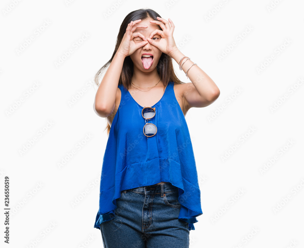 Young asian woman over isolated background doing ok gesture like binoculars sticking tongue out, eyes looking through fingers. Crazy expression. Young asian woman over isolated background doing ok gesture like binoculars sticking tongue out, eyes looking through fingers. Crazy expression.