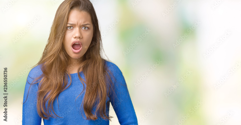 Young beautiful brunette woman wearing blue sweater over isolated background In shock face, looking skeptical and sarcastic, surprised with open mouth Young beautiful brunette woman wearing blue sweater over isolated background In shock face, looking skeptical and sarcastic, surprised with open mouth