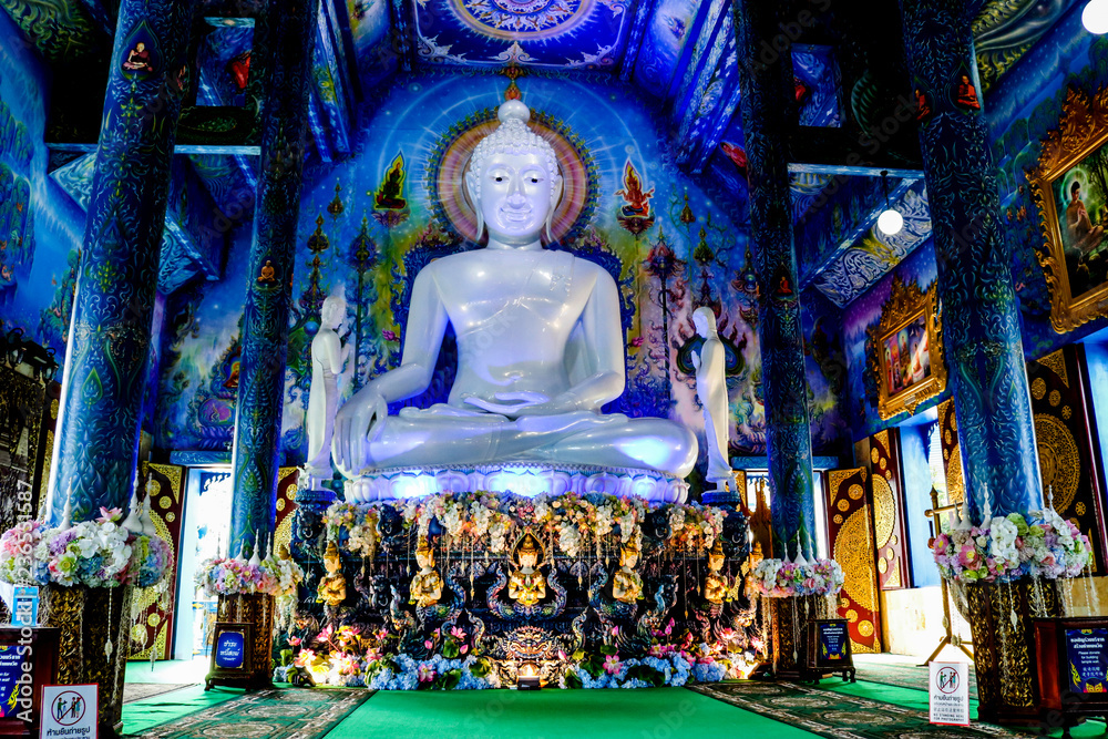 Fototapeta premium White Buddha statue in blue temple with beautiful Thai handicraft pattern.Thailand Chiang rai : 9 November 2018