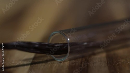 Vanilla Pod is slowly Pulled Out of a Glass Tube (Hand Visible), Closeup