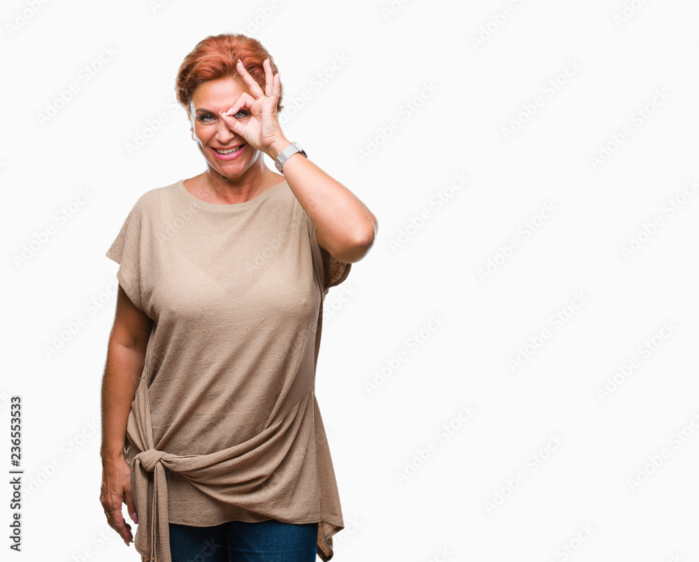 Atrractive senior caucasian redhead woman over isolated background doing ok gesture with hand smiling, eye looking through fingers with happy face. Atrractive senior caucasian redhead woman over isolated background doing ok gesture with hand smiling, eye looking through fingers with happy face.